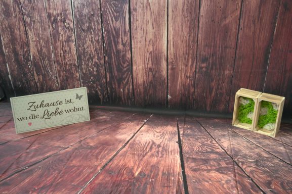 Holzoberfläche mit einem Schild und einer kleinen Kiste mit Moos.