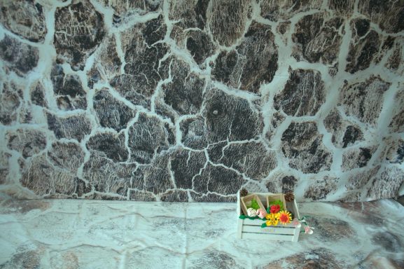 Gestrichelte Wand mit erdigen Farben und kleiner Kiste mit buntem Inhalt.