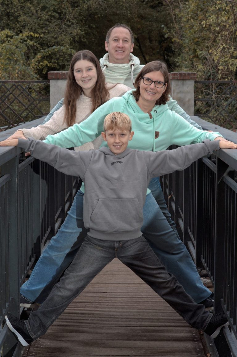 Vier Personen stehen auf einer Brücke, posieren in einer kreativen, gestreckten Form.