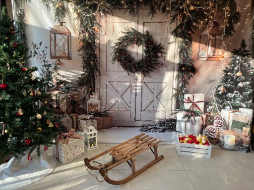 Weihnachtliche Dekoration mit Tannenbaum, Geschenken und einem Schlitten vor einer Holzoberfläche.