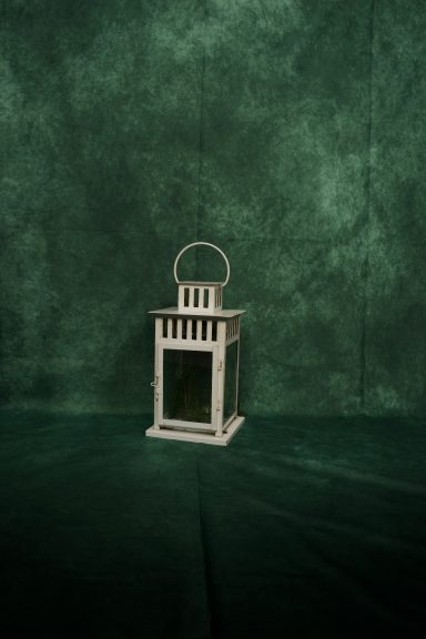 Weiße Laterne mit Griff vor grünem Hintergrund.